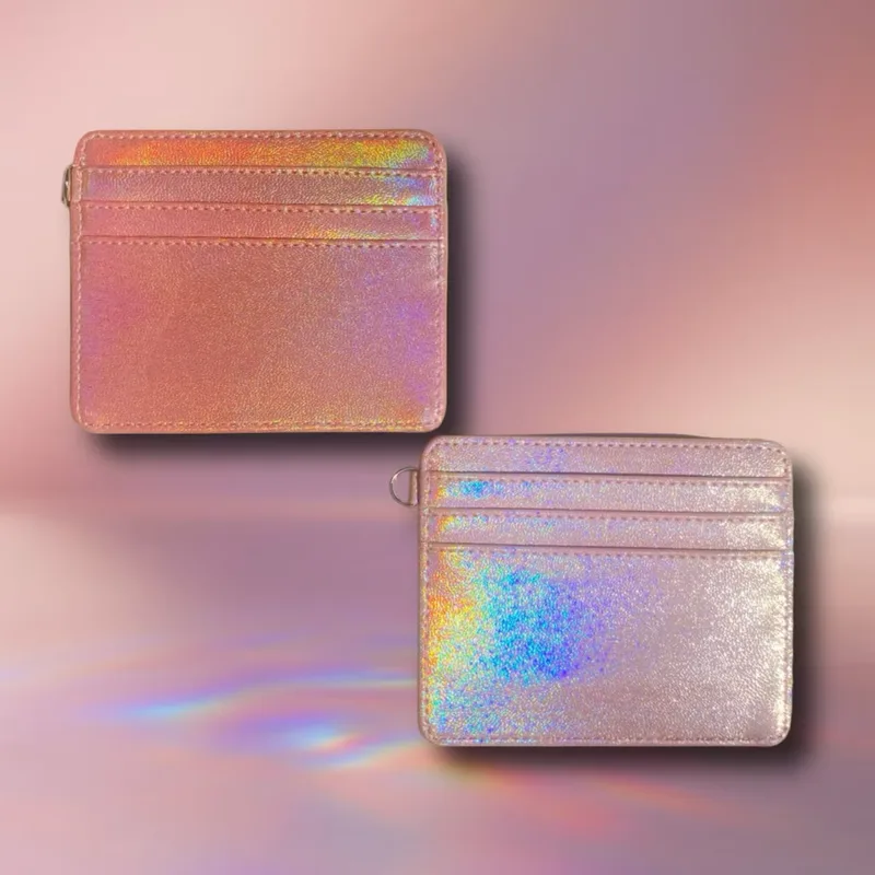 Dua dompet kartu berpermukaan hologram, satu merah muda keemasan dan satu perak dengan pantulan pelangi, di atas latar merah muda