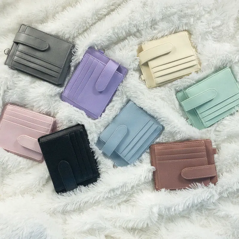 Sembilan card holder dengan tali pengunci dalam berbagai warna berserakan di atas kain berbulu putih
