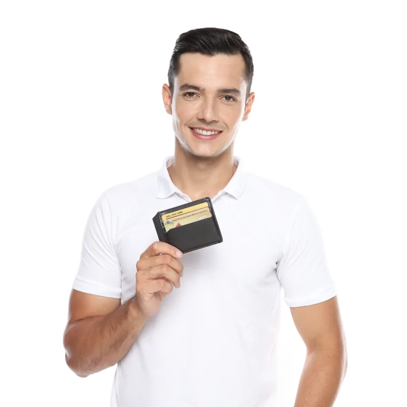 Pria berkaus polo putih tersenyum sambil memegang dompet tipis berwarna hitam berisi beberapa kartu di depan dadanya, berlatar putih