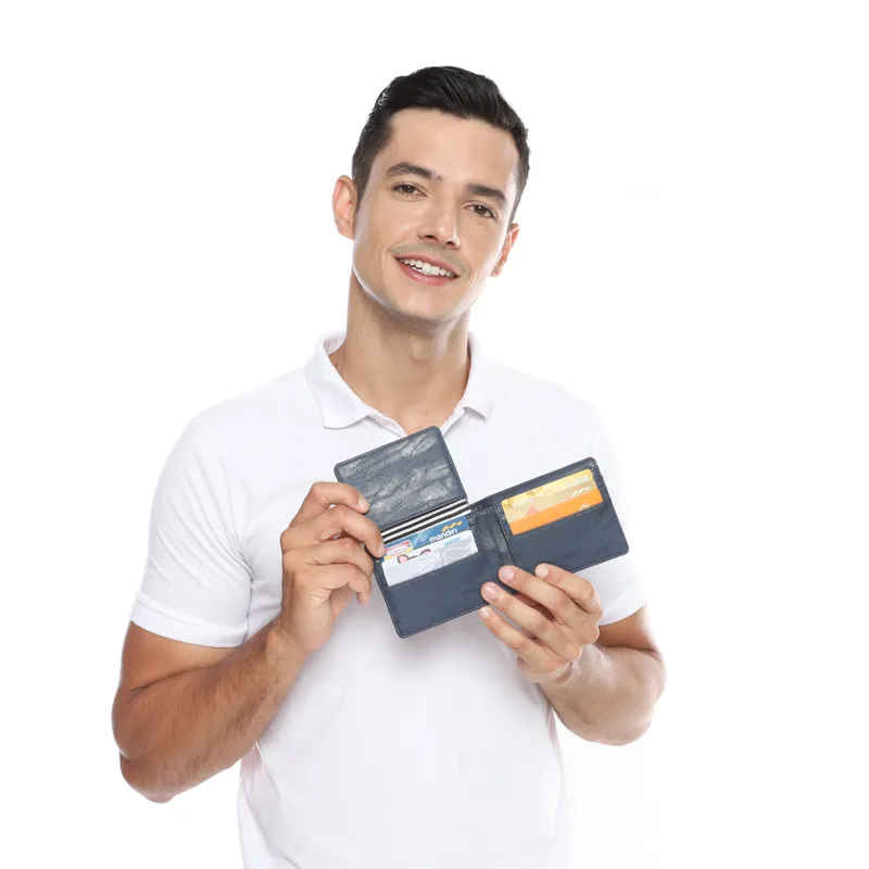 Pria memegang dompet bifold biru dongker terbuka dengan panel jendela kartu identitas yang diangkat, memperlihatkan kartu di baliknya dan kartu di slot sisi kanan