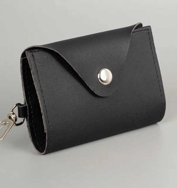 Gantungan kunci model dompet STNK hitam dengan tutup melengkung berkancing logam dan kait kunci logam di sisi kiri bawah, di atas latar abu-abu
