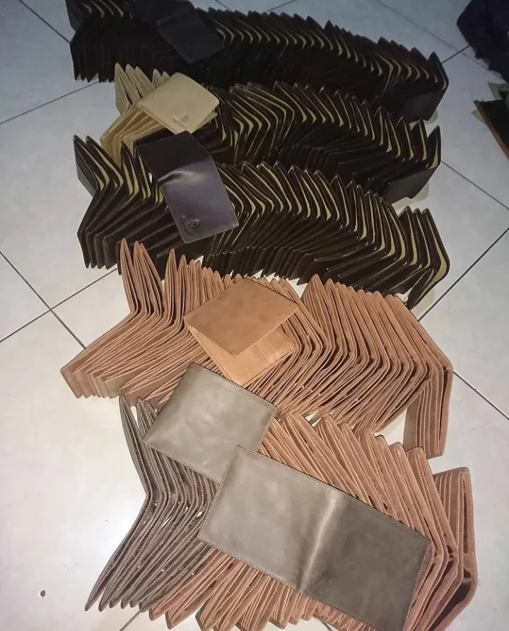 Ratusan dompet lipat cokelat tua, cokelat muda, dan abu-abu dijajarkan miring berbaris di lantai keramik putih