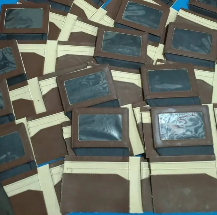 Banyak dompet lipat cokelat tua dengan jendela plastik bening dan lapisan krem yang belum disatukan, tersusun bertumpuk di atas meja