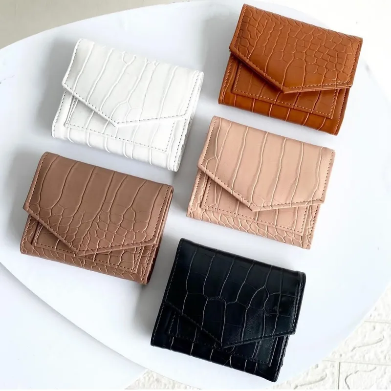 Enam dompet lipat bertekstur croco berwarna putih, oranye, cokelat muda, merah muda pucat, cokelat susu, dan hitam di atas permukaan putih