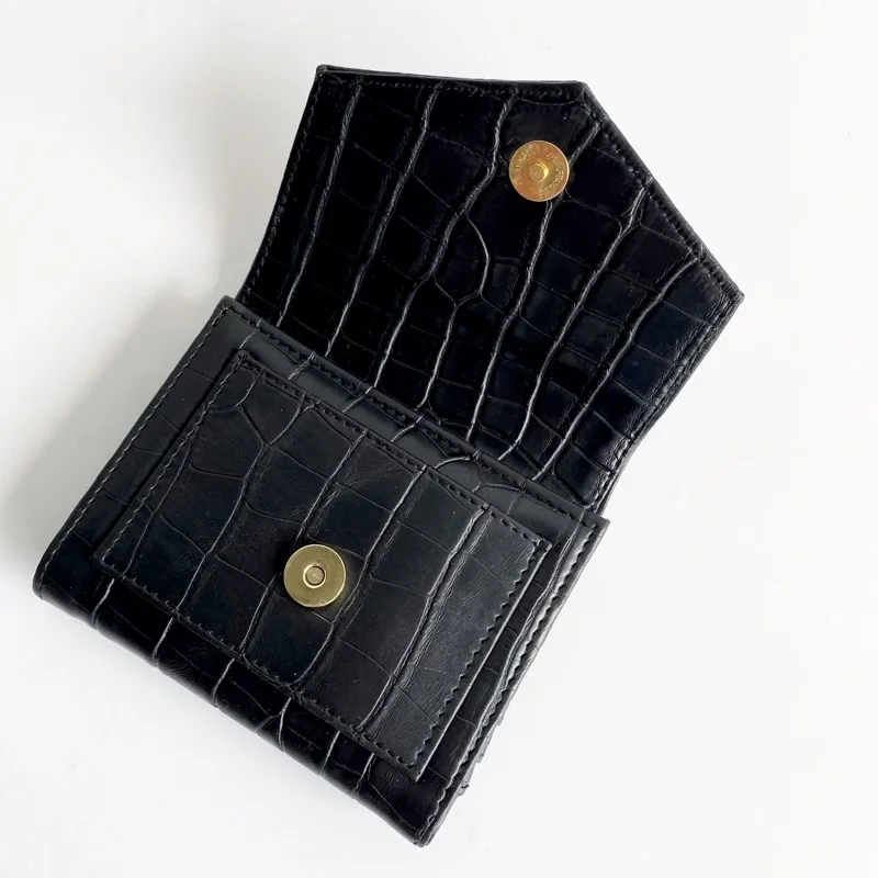 Dompet lipat hitam bertekstur croco dalam keadaan terbuka, memperlihatkan tutup berbentuk amplop dan dua kancing magnet berwarna emas