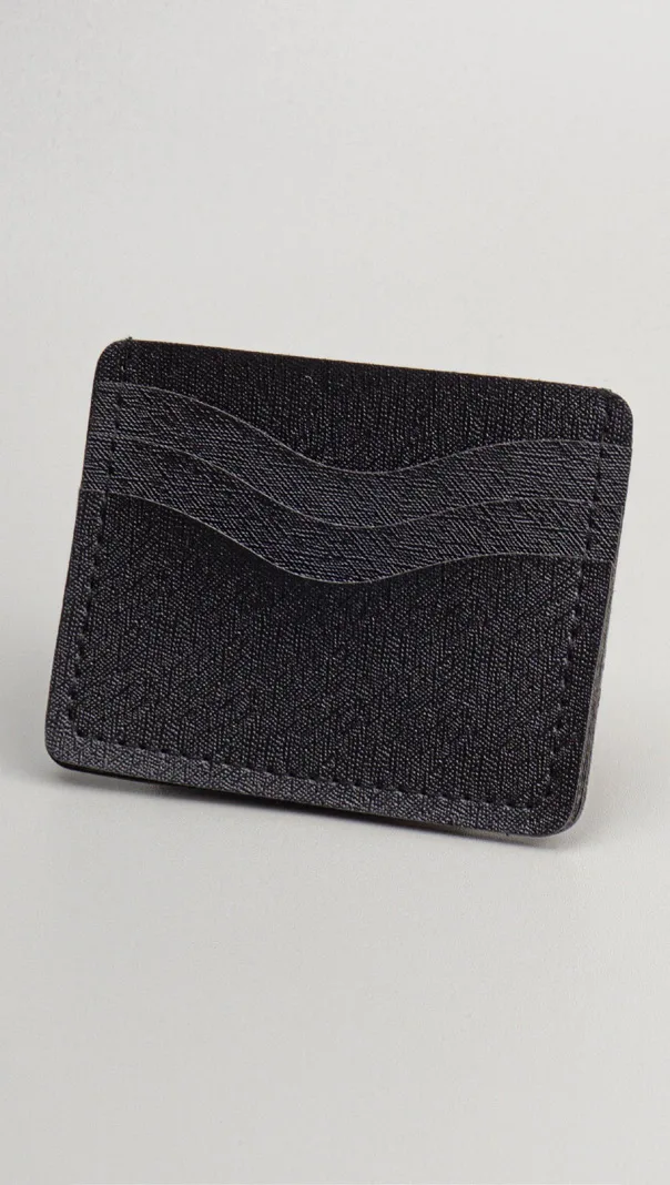 Card holder kulit hitam dengan motif garis bergelombang di bagian depan, tiga slot kartu, berdiri miring di atas latar putih