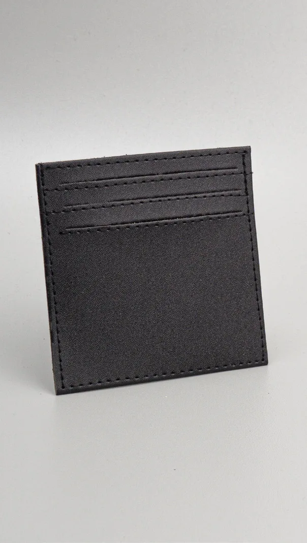 Card holder kulit hitam polos empat slot tanpa kancing berdiri miring di atas latar abu-abu