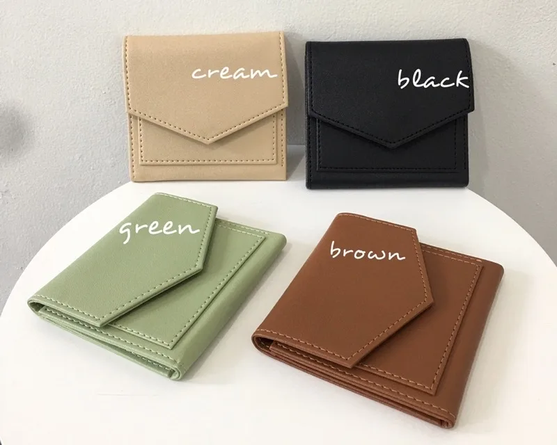 Empat dompet lipat model amplop berwarna krem, hitam, hijau muda, dan cokelat dengan tulisan nama warnanya, diletakkan di atas meja bundar putih