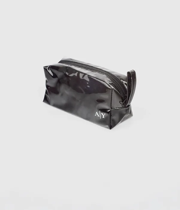Pouch berbentuk kotak warna hitam mengilap dengan ritsleting di atas dan tali kecil di samping, dengan inisial A dan Y berwarna putih berukuran kecil di sudut kanan bawah