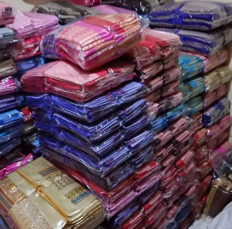 Tumpukan tinggi pouch kain berbagai warna merah muda, ungu, biru, dan emas yang sudah dikemas dalam plastik bening per buah