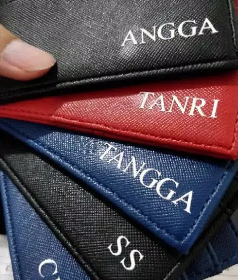 Card holder hitam, merah, dan biru dengan nama penerima tercetak putih di sudutnya