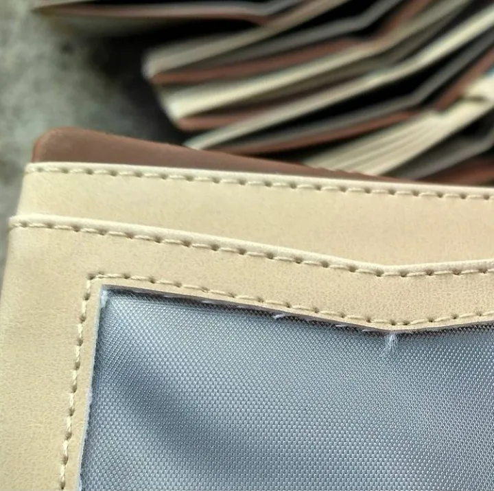 Detail jahitan tepi pada dompet krem dengan lapisan dalam kain abu-abu