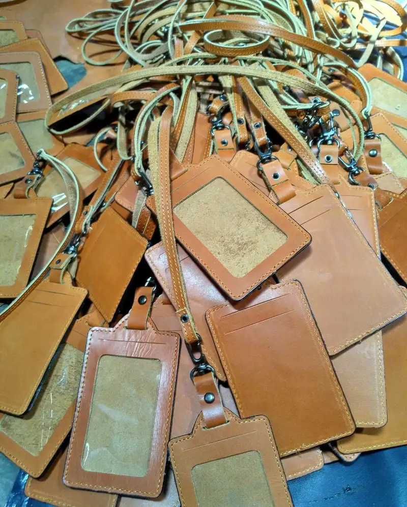 Tumpukan ID card holder kulit cokelat lengkap dengan tali lanyard dan pengait logam