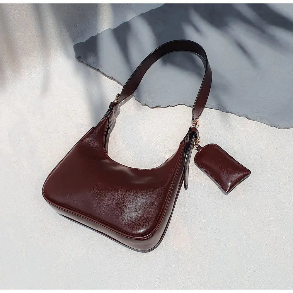 Benita Bag cokelat tua dengan pouch kecil di atas kain abu-abu